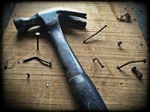 A hammer and nails on a wooden workbench