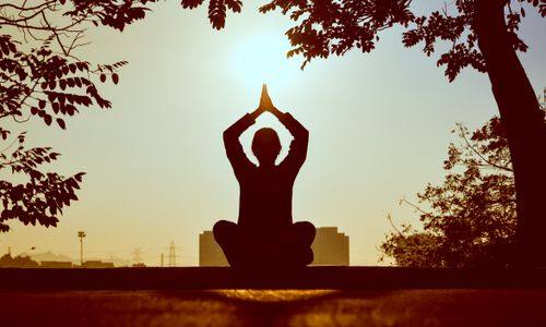 A person meditating at sunrise