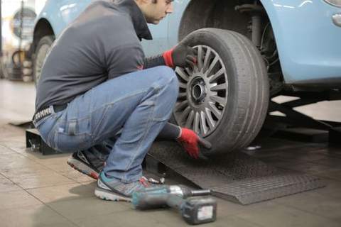 A mechanic checking a car tire in a garage