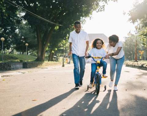 A family walking and riding bikes on a park path