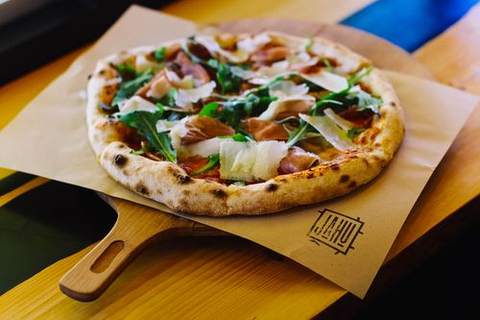 A pizza topped with fresh greens on a wooden board