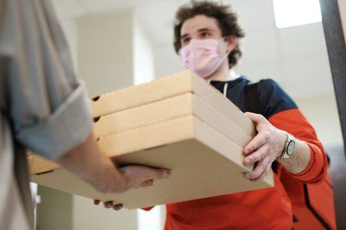 A delivery driver handing over pizza
