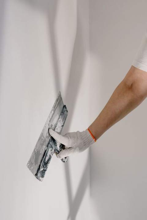 A hand fixing something on a white wall